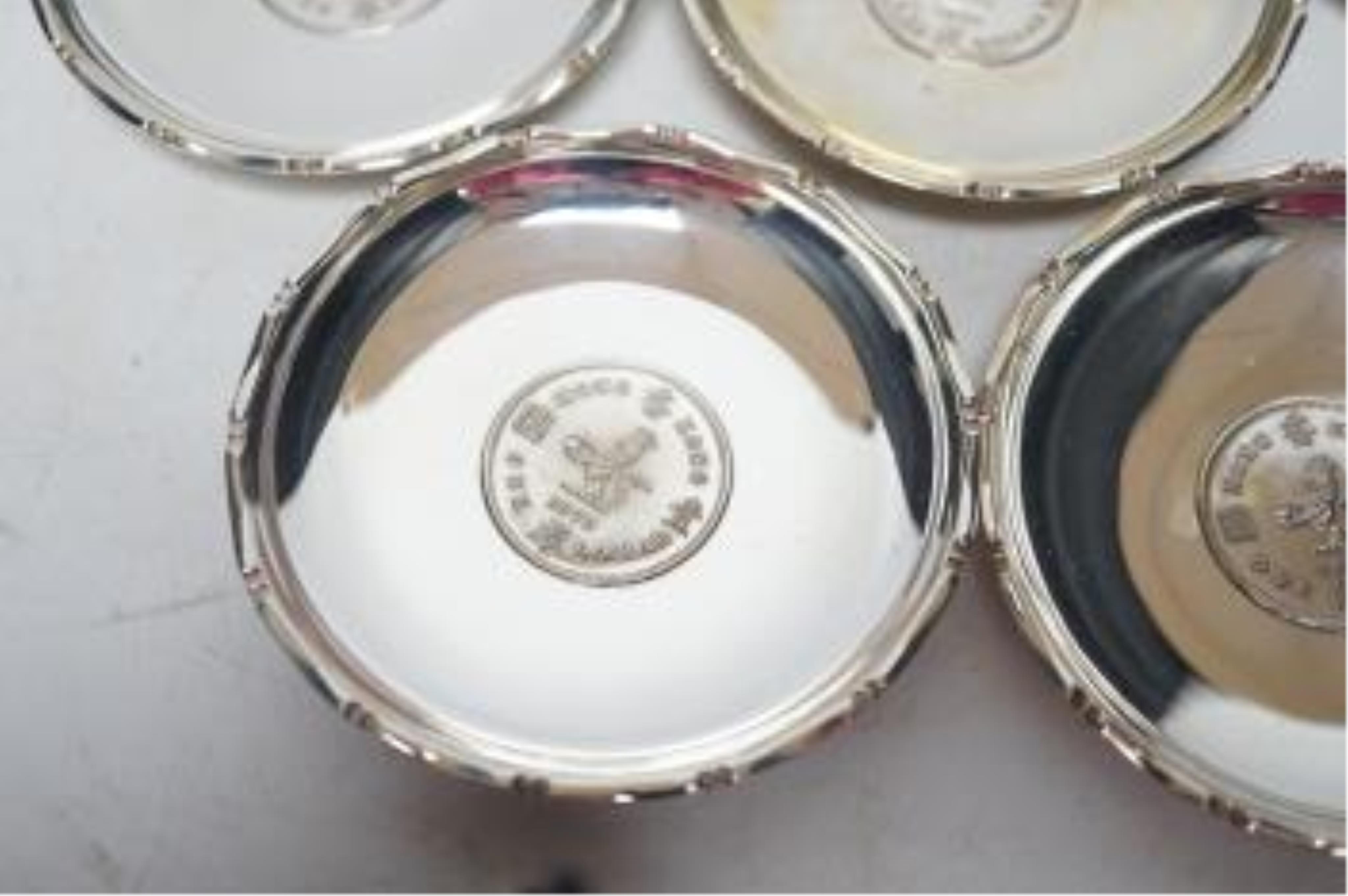 A set of seven Hong Kong sterling small dishes with inset coin, signed 'Sammy', diameter 86mm, gross weight 10.2oz. Good condition.